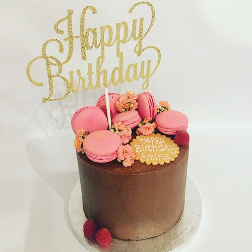 A Chocolate fudge cake filled with layers of chocolate buttercream. Fonoshed with smooth edges of buttercream, topped with 6 chewy pink macarons and fresh flower buds. 